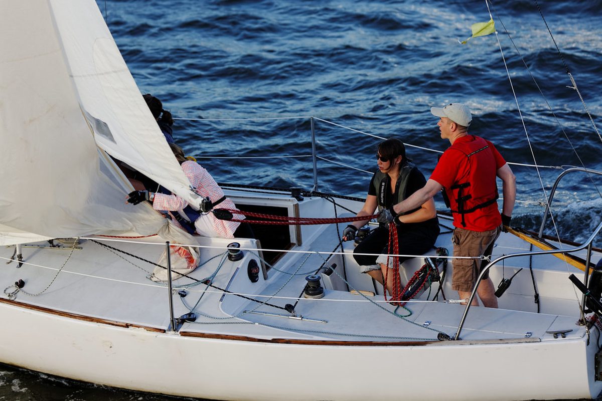 A sailor hoisting the mainsail